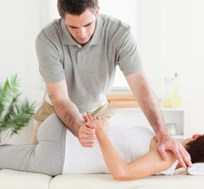 A masseur is stretching a woman's arm