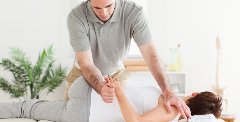 A masseur is stretching a woman's arm